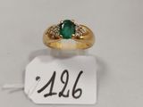 gros plan d'une bague en or avec une pierre verte