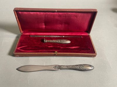 un stylo en argent et une cuillère en argent dans un étui rouge