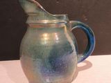 une carafe bleue et verte posée sur une table blanche