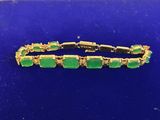 un bracelet en or orné de pierres vertes sur un fond bleu