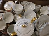 a box full of white and gold china plates and bowls