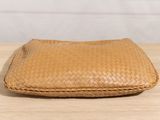 a brown woven purse sitting on top of a wooden table