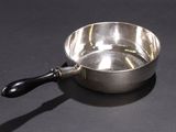 a small silver bowl with a black handle on a table