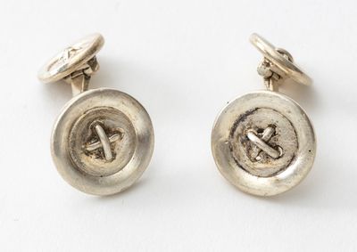 un gros plan sur une paire de boutons argentés posés sur une surface blanche