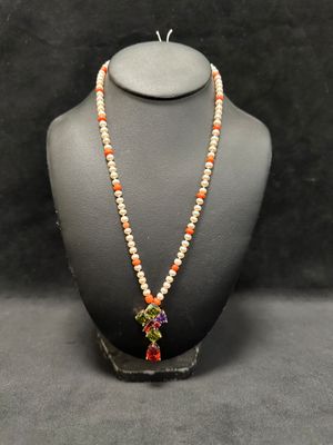 a necklace with orange and white beads on a mannequin