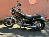 a black motorcycle parked in front of a pink wall