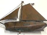 a metal model of a sailboat on a white surface