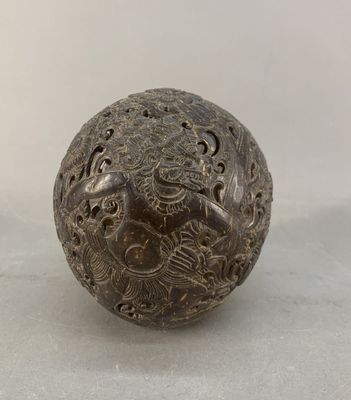 une vieille boule en métal ornée de gravures, posée sur une surface blanche