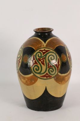 un vase noir et or posé sur une surface blanche