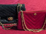 two black and red purses with gold chains on a red surface