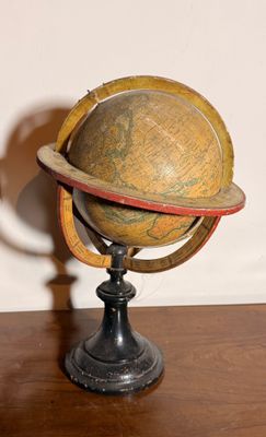 un petit globe en bois posé sur un socle, sur une table
