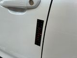 the door handle of a white car with a sticker on it