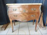 a small wooden chest of drawers on a tiled floor