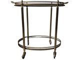 a brass bar cart with a glass shelf on wheels
