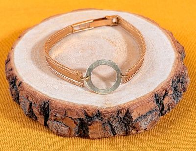 a bracelet with a circle on it sitting on a tree stump
