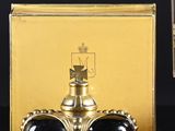 une boîte dorée ornée d'une couronne, à côté d'un verre