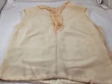 cream colored top with lace trim on top of a white bed