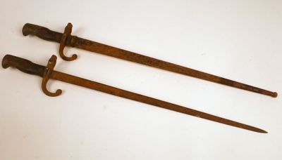une paire de deux vieilles épées en bois posées sur une surface blanche