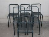 four metal chairs are lined up against a wall in a parking lot
