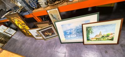 de nombreux tableaux encadrés posés sur une étagère dans une pièce
