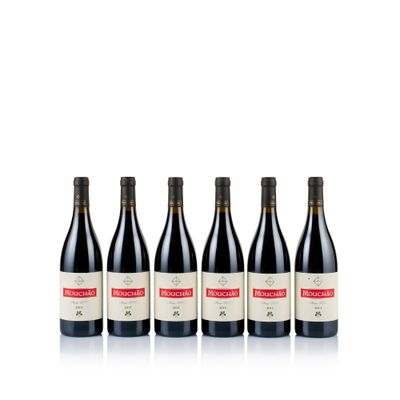 four bottles of red wine lined up on a white surface