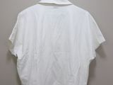 the white shirt is hanging on a hanger on the wall