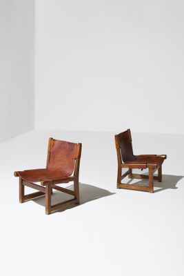 deux fauteuils en cuir marron posés sur un sol blanc