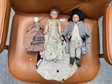 two dolls that are sitting on top of a chair