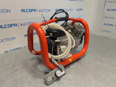 a red air compressor sitting on top of a cement floor
