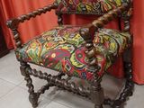 a chair with a colorful upholstered seat and a red curtain