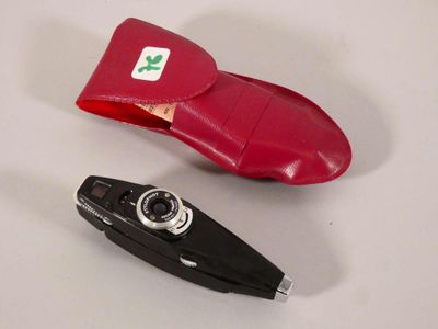 une paire de chaussures en cuir rouge et un appareil photo posés sur une surface blanche