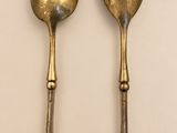 two spoons and a fork are sitting on a white surface