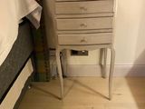 une petite table sur laquelle est posée une lampe, à côté d'un lit