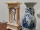 un vase bleu et blanc posé sur une table à côté d'une horloge