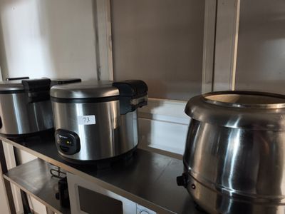 Plusieurs casseroles et poêles en acier inoxydable sont posées sur une étagère dans une cuisine