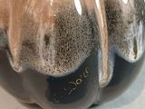 a close up of a black and brown vase on a table