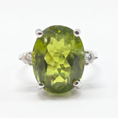 gros plan d'une bague avec une pierre verte entourée de diamants