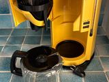 a yellow coffee maker sitting on a blue tiled floor