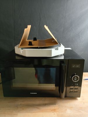 un micro-ondes sur lequel est posée une boîte à pizza