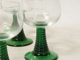 three green wine glasses sitting on top of a table next to each other