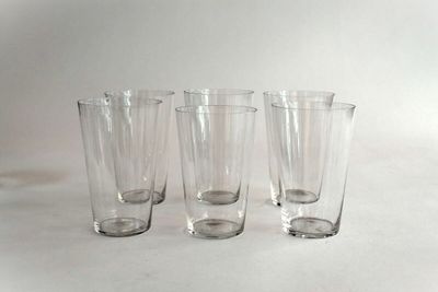 four clear glasses are lined up on a white surface