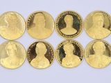 six gold coins with portraits of people on them on a white surface