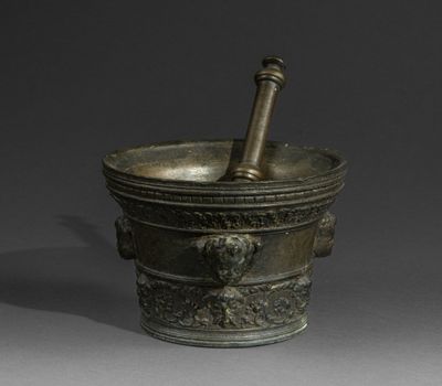 a metal mortar with a wooden handle on a gray surface