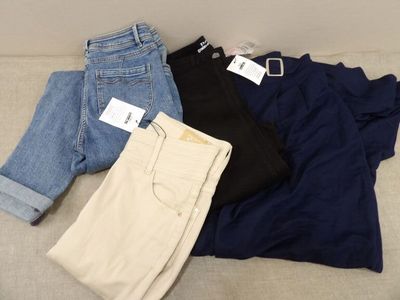 trois paires de jeans sont posées sur un canapé