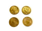 quatre types différents de pièces d'or reposant sur une surface blanche
