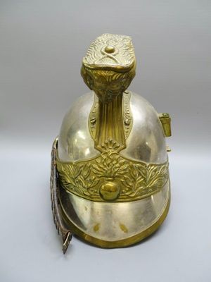 un vieux casque en laiton orné d'une plume sur le sommet
