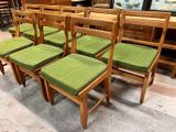 six chairs with green cushions on them in a room