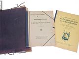 Trois livres sont posés sur une table, avec une horloge en arrière-plan.