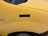 a close up of a yellow car parked in a parking lot
