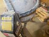 cement mixer sitting in a garage with a wooden pallet in front of it